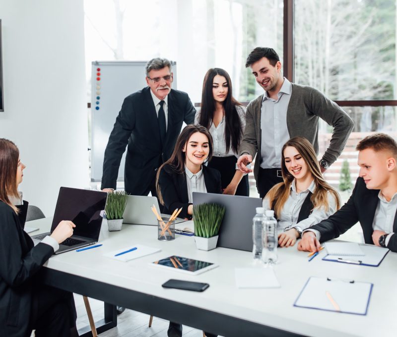 Staff meeting. Group of   young modern people in smart casual wear discussing something while working in the creative office . Business time..